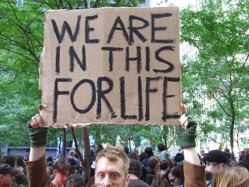 Manifestante en #occupywallstreet con pancarta que dice We are in this for life. Foto de Cris Blanco.